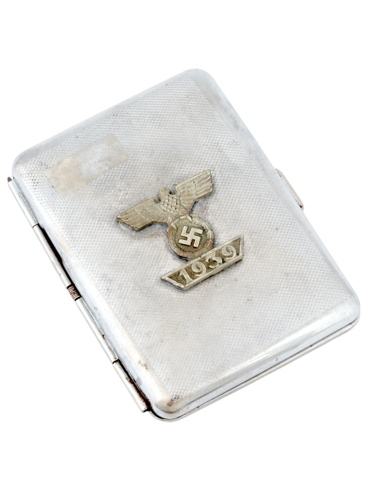 GERMAN WWII WEHRMACHT OFFICERS CIGARETTE CASE: A World War II model Nazi German Wehrmacht officers steel cigarette case with a hinged lid. The lid is decorated with a chased design, and an overlay representing a Nazi eagle clutching a swastika ins