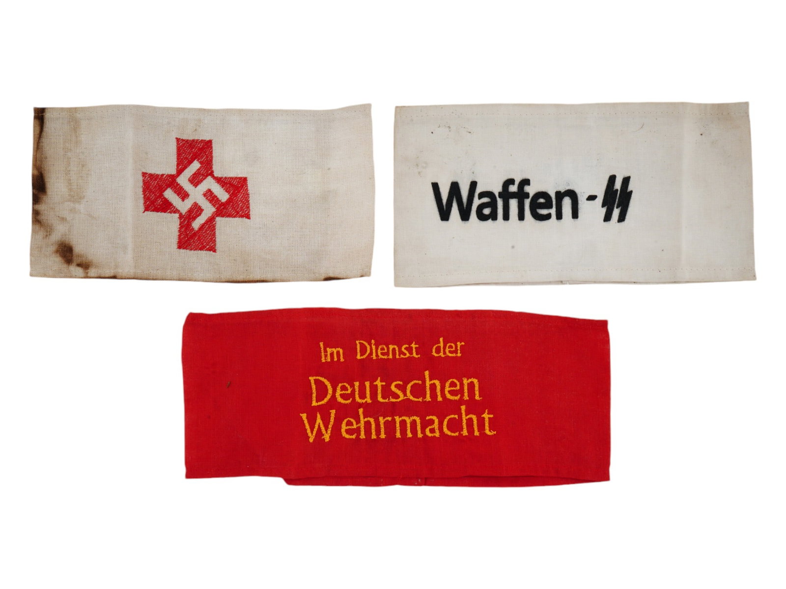GROUP OF THREE GERMAN WWII TYPE FABRIC ARMBANDS: A collection of three WWII type Nazi German Third Reich fabric armbands. The collection includes a Waffen SS armband, a hand embroidered red cross with swastika, the NSDAP Red Cross symbol and a red h
