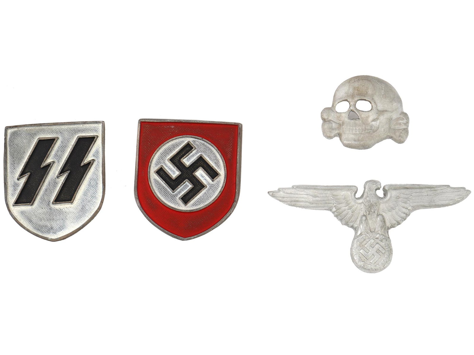 GROUP OF FOUR GERMAN WWII TYPE METAL HAT BADGES: A group of four WWII Nazi German enamel metal hat badges. The collection includes a shield for an SS pith helmet, covered with enamel in black and silver shades and helmet shield depicting a swastika 