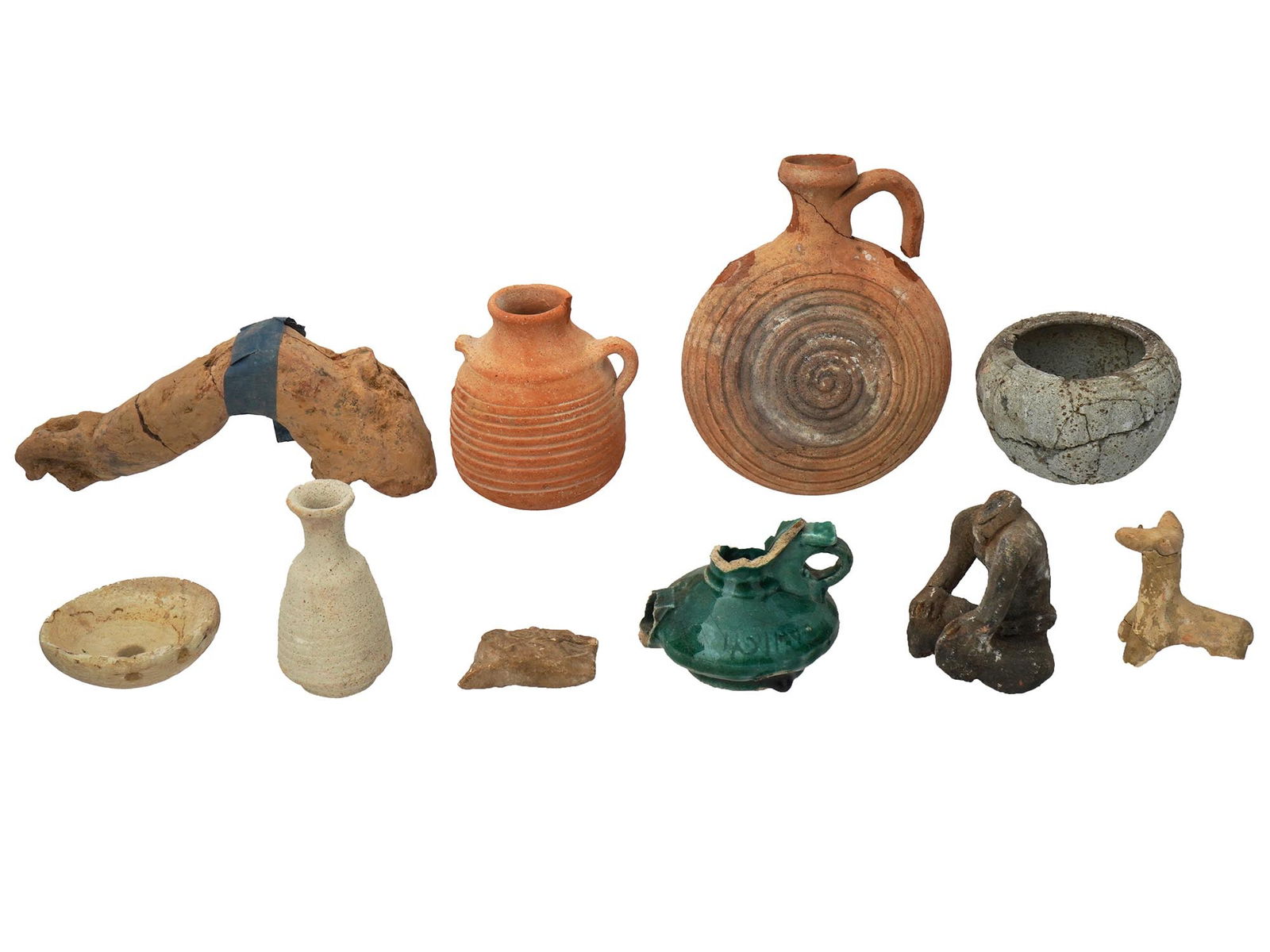 GROUP OF ANCIENT ARTIFACTS CA 500 BC TO 500 AD: A group of ancient artifacts, circa 500 BC to 500 AD. The collection includes a terracotta pilgrim flask with a flattened, lentoid shaped body and a curved handle on the side. A terracotta jug with a