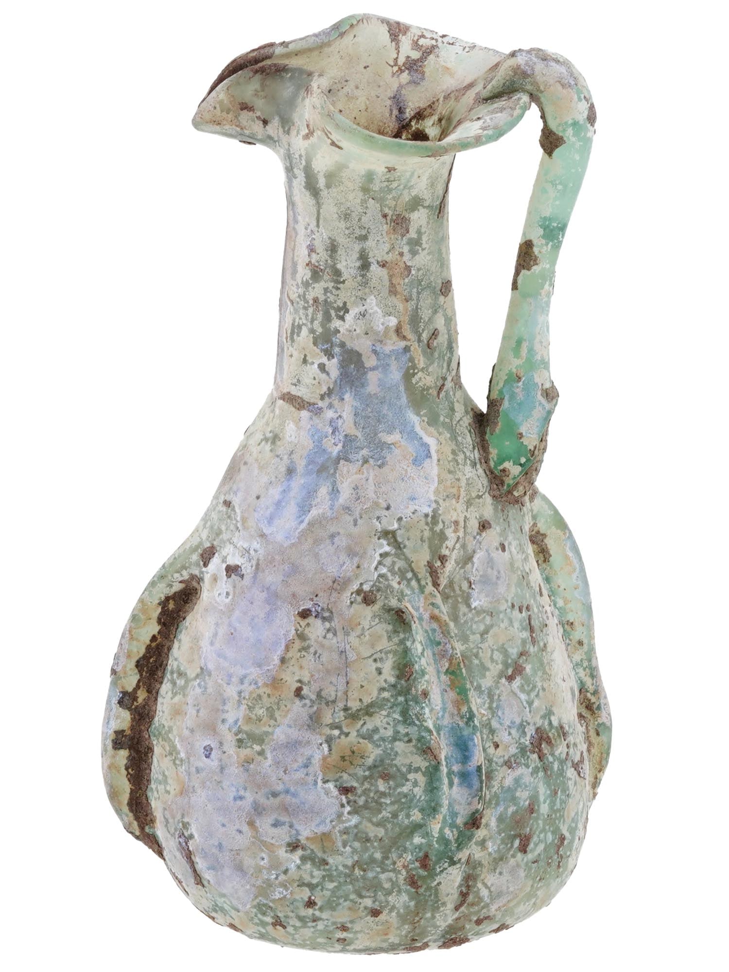 ANCIENT ROMAN GLASS OINOCHOE JUG 100 TO 300 AD: An ancient Roman glass oinochoe jug or pitcher, circa 100 to 300 AD. The jug, made of light green glass, has an ovoid ribbed body with a tall cylindrical neck and trefoil lip. An undulating trail arou