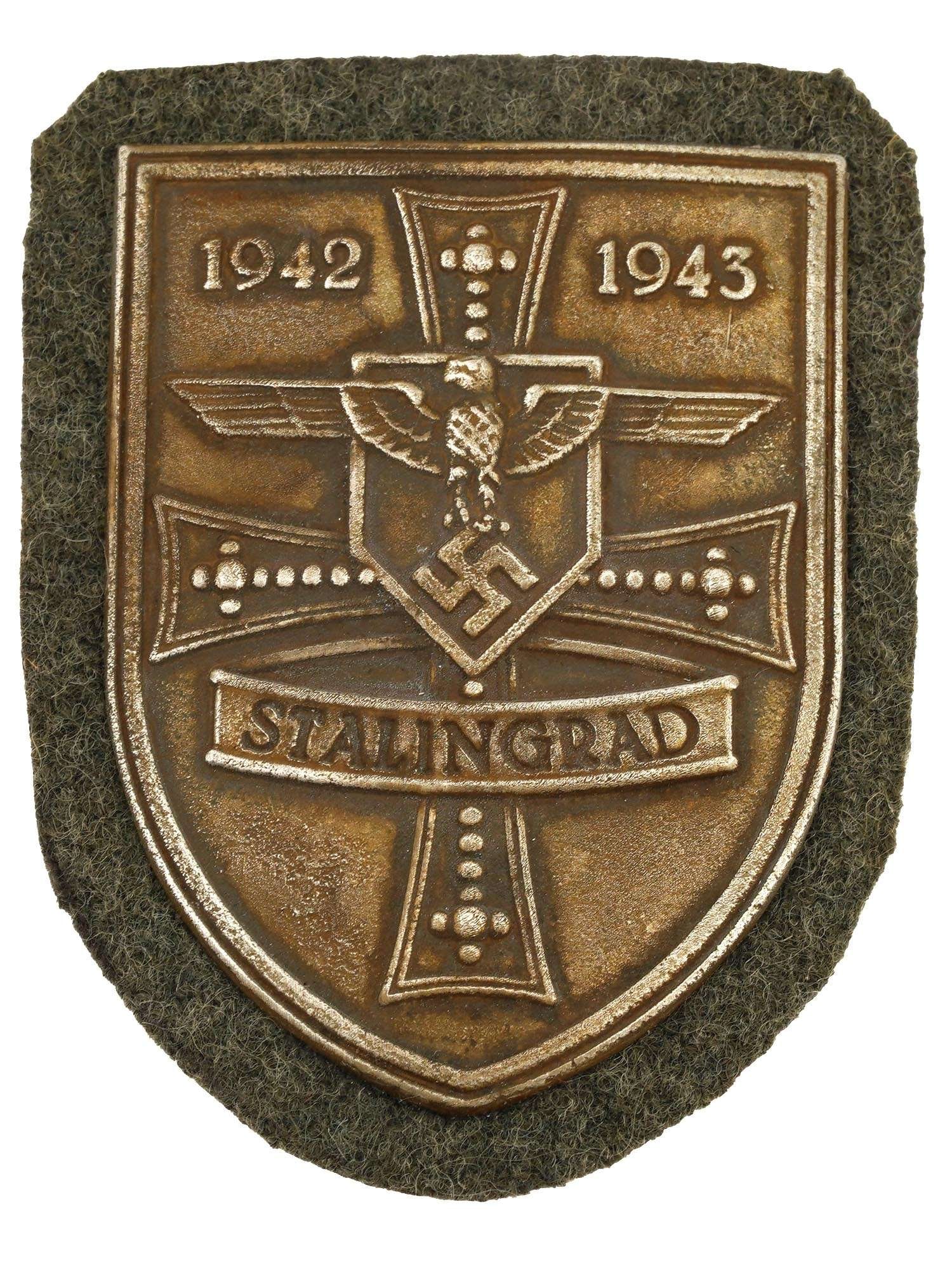 WWII NAZI GERMAN MILITARY AWARD STALINGRAD SHIELD: A World War II type German military decoration, the Stalingrad Shield. The zinc shield shaped badge features an eagle with a swastika, a cross and inscription 1942 to 1943 Stalingrad. The Battle of St