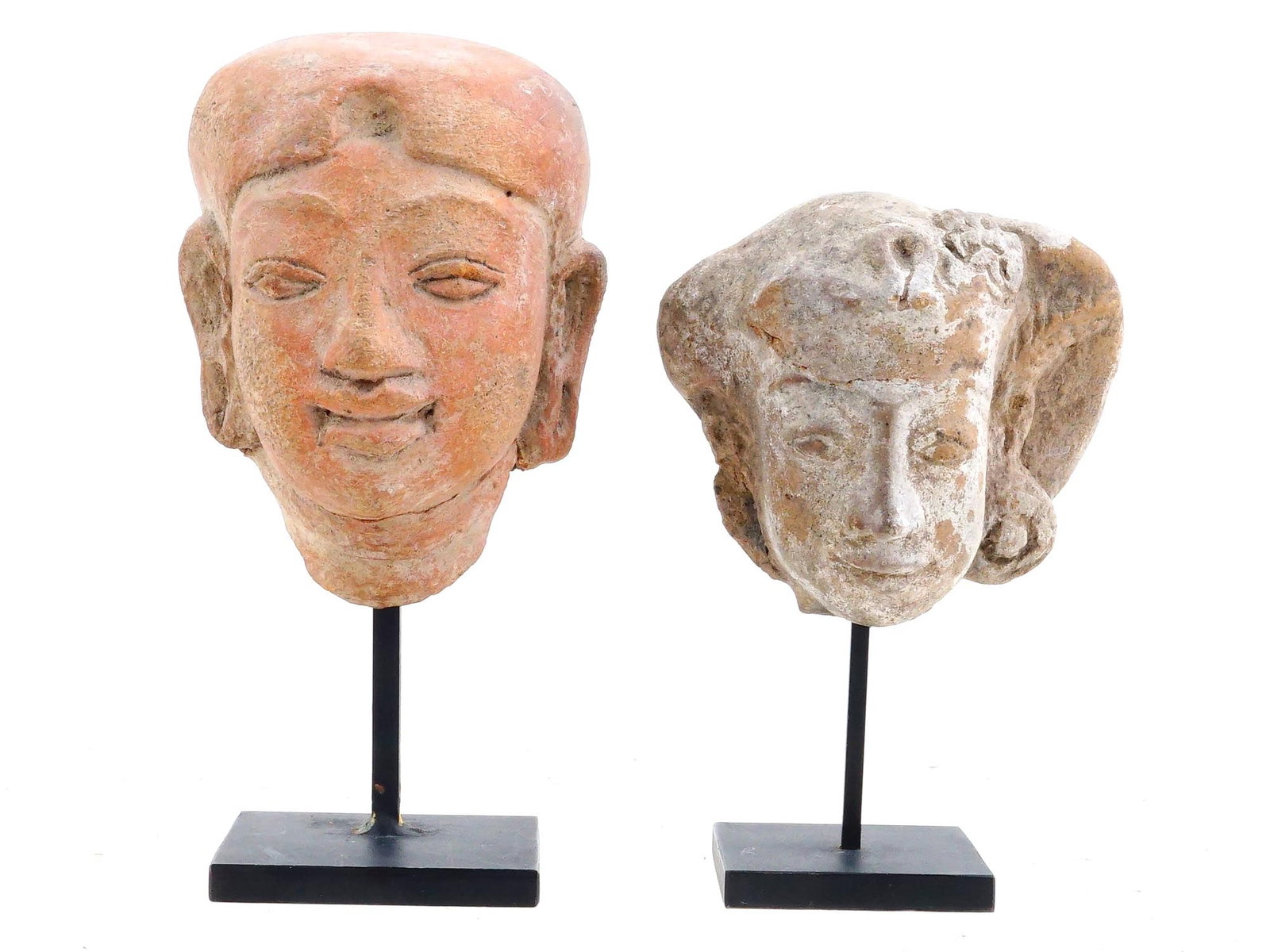 ANCIENT GANDHARA CULTURE EARTHENWARE HEAD SCULPTURES: A pair of ancient Pakistan Gandhara culture earthenware head sculptures. Dates to the 400 AD. The head sculptures represent Indo Buddhist deities with smooth facial features and elongated ears. Labele
