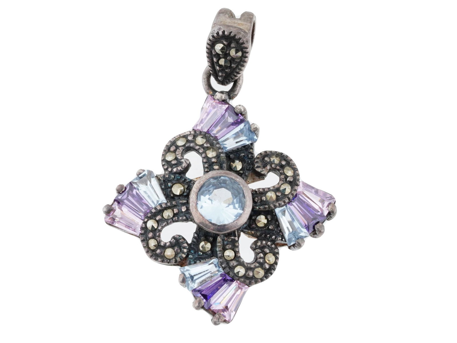 MEXICAN SILVER SAPPHIRE MARCASITE PENDANT: A Mexican silver pendant featuring an intricate design with a central light blue sapphire, surrounded by ornate silver detailing. The silver setting is decorated with small marcasite stones, adding a 