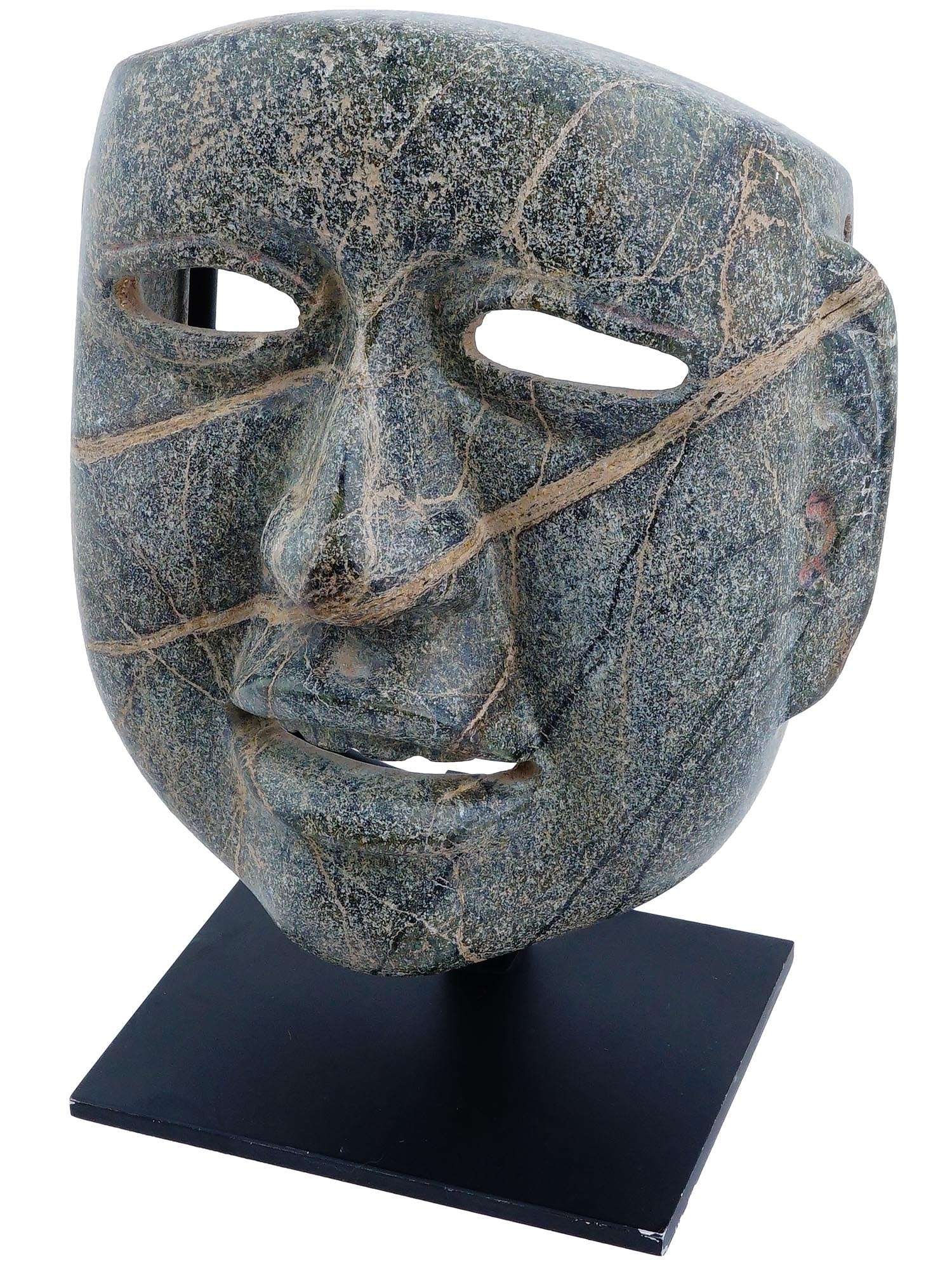 ANCIENT MESOAMERICAN OLMEC HEAD MASK SCULPTURE: An ancient Olmec mask from Pre Columbian America carved of natural jade stone. The mask is a smoothly polished surface of the face with openings for the eyes and mouth. On the sides and top of the hea