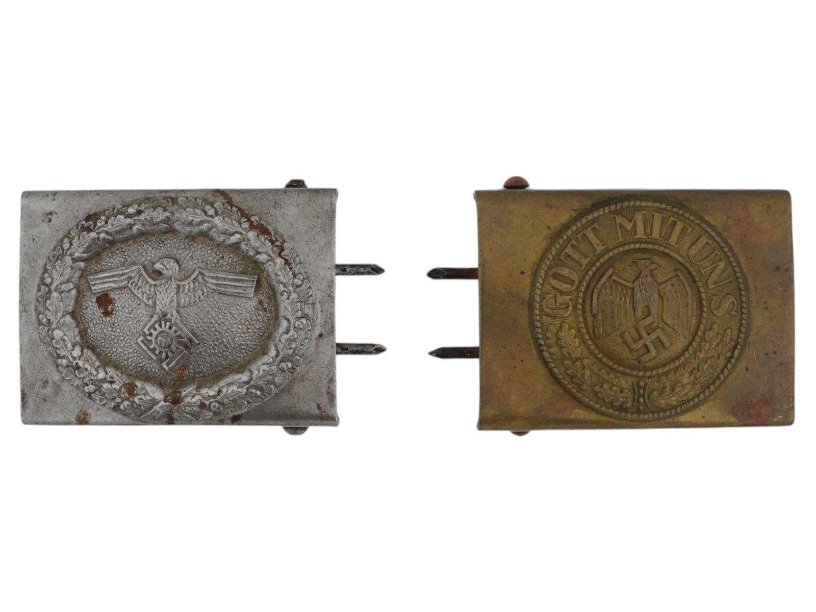 TWO WWII NAZI GERMAN THIRD REICH WEHRMACHT BELT BUCKLES: A lot of two WWII Nazi German Third Reich Wehrmacht belt buckles. The buckle on the left features a detailed design including a central eagle emblem with outstretched wings, beneath which is a swastik
