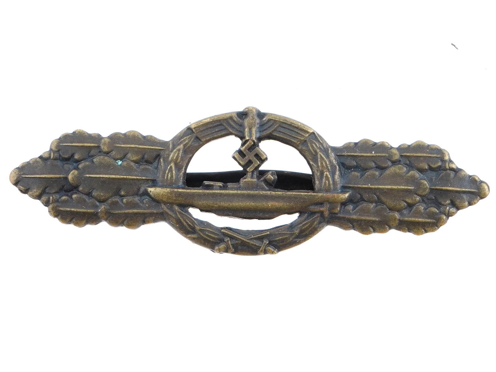 WWII NAZI GERMAN KRIEGSMARINE U BOAT BADGE: A WWII German U Boat badge or clasp. Featuring an image of a boat and a Nazi eagle swastika insignia, and oak leaves on the sides. Inscribed on the backside, Entwurf Peekhaus, AUSF Schwerin Berlin 68.