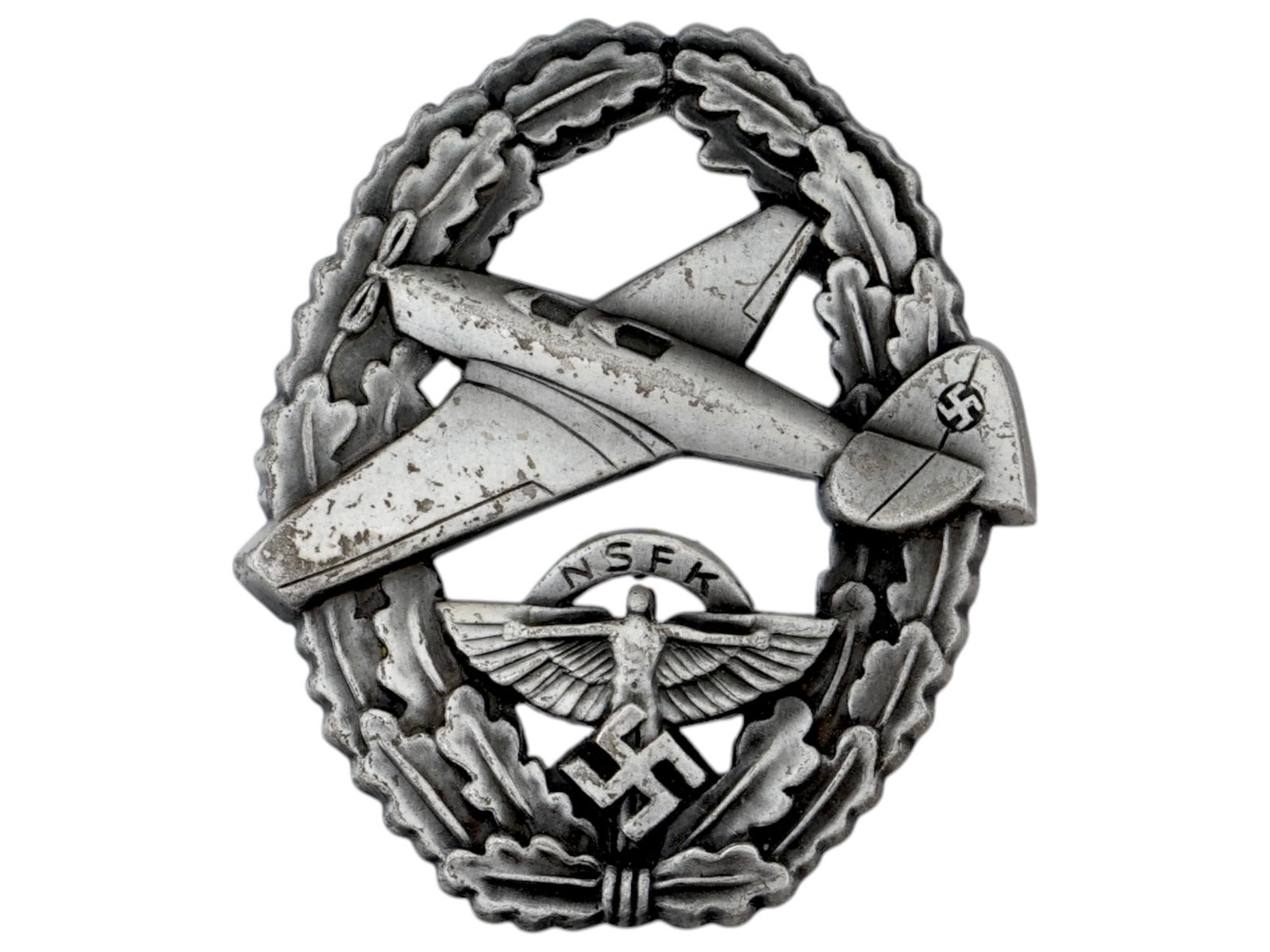 WWII TYPE NAZI GERMAN NSFK MOTORIZED PILOTS BADGE: A WWII type Nazi German NSFK National Socialist Flyers Corps motorized pilots badge. The badge features a large airplane in the center of an oak leaf wreath at the top and the NSFK symbol, a winged ma