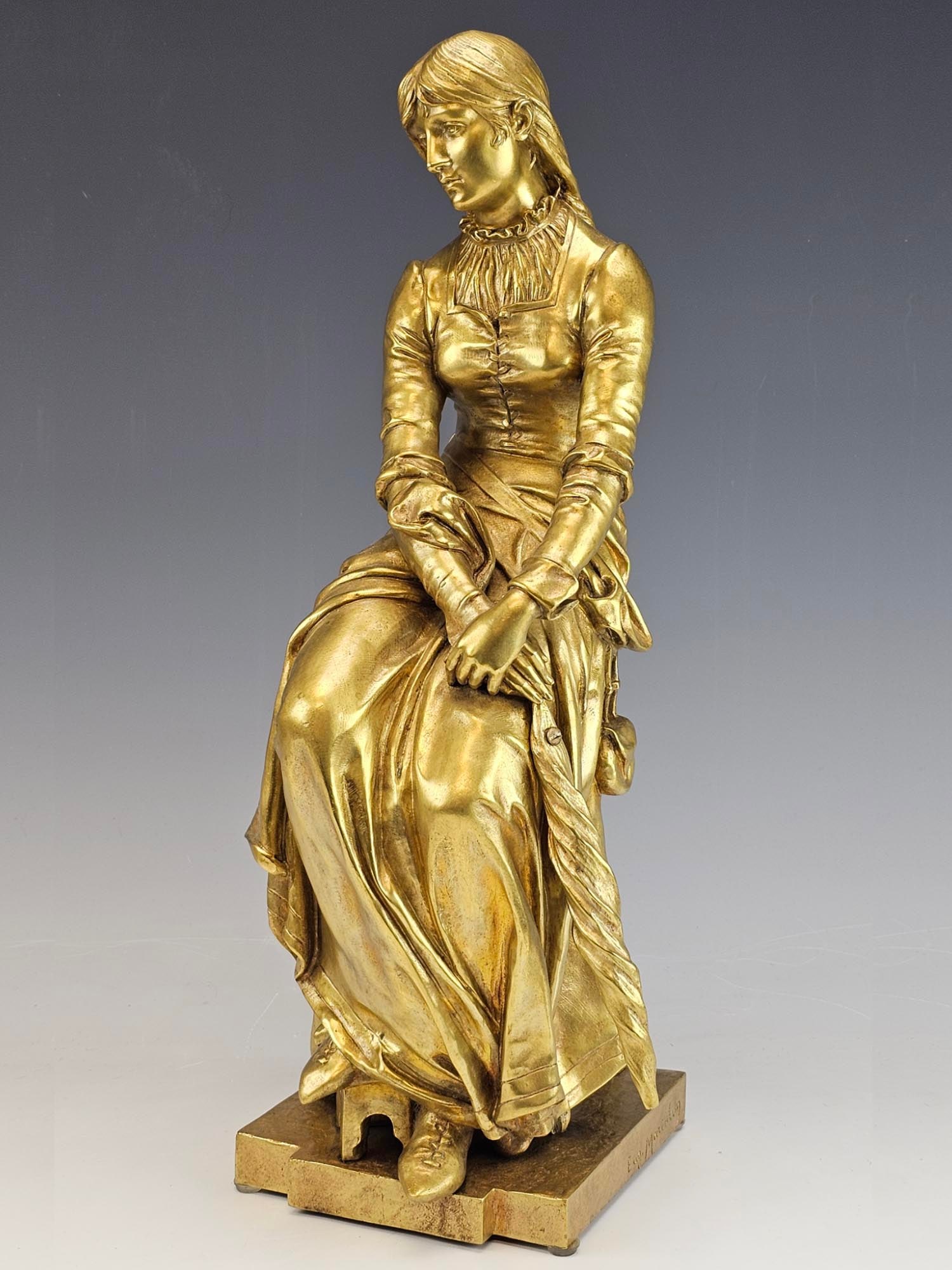 19 C FRENCH GILT BRONZE SCULPTURE BY EUGENE MARIOTON: An antique 19th century gilt bronze sculpture by Eugene Marioton, French, 1857 to 1933. The bronze depicts a lady sitting and holding an umbrella in her hand. Signed with casting, Eugene Marioton on o