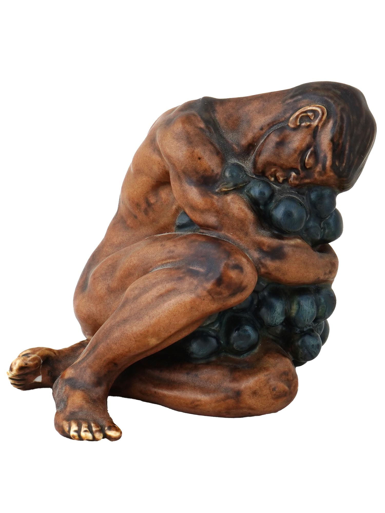 DANISH CERAMIC FIGURINE WITH GRAPE SIGNED KAI NIELSEN: A Danish ceramic sculpture depicts a nude figure embracing an exaggerated grape cluster, original design by Kai Nielsen, 1882 to 1924, for Bing and Grondahl in Copenhagen. Marked on the bottom with a