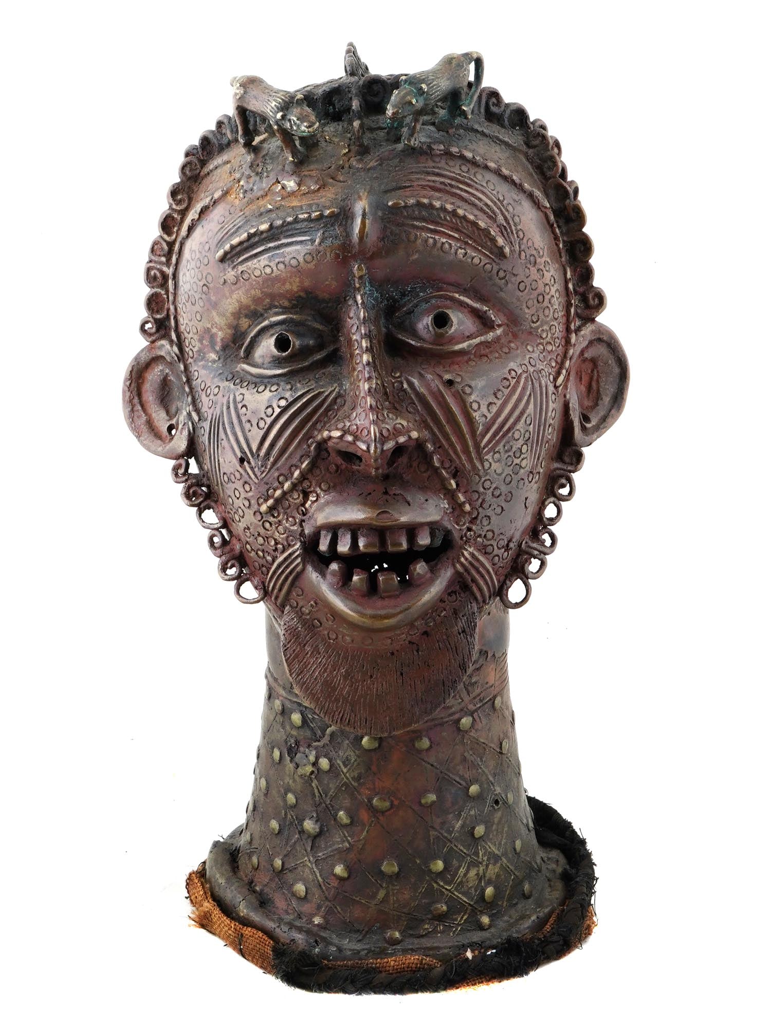 WEST AFRICAN NIGERIAN BENIN YORUBA FETISH BRONZE HEAD: A vintage bronze Yoruba fetish head from Benin, Nigeria, West Africa. The face is characterized by prominent features, including expressive eyes and a wide mouth displaying teeth.T he head is adorned 