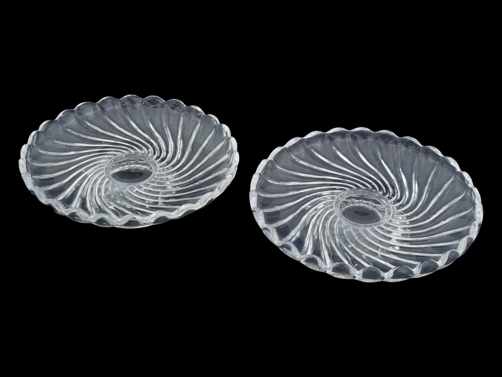 PAIR OF VTG FRENCH GLASS CANDY BOWLS BY BACCARAT: A pair of vintage French glass candy bowls made by Baccarat. Bowls on a low stem, round in shape, with a wavy edge and a spiral pattern. Each bears an etched Baccarat mark on the bottom. Table and Des