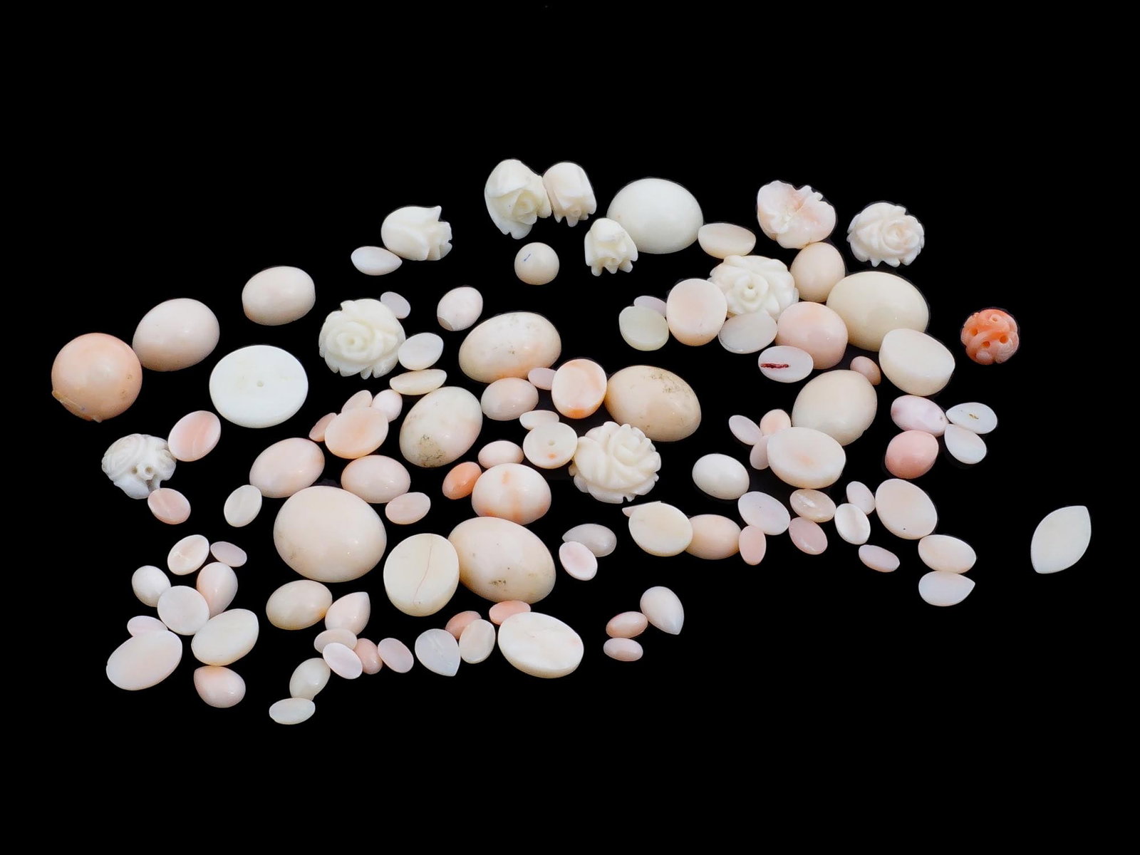 GROUP OF ASSORTED HAND CARVED CORAL AND STONE BEADS: A group of assorted hand carved coral and stone beads in various sizes and shapes. The lot consists of round and oval cabochons and beads, flat from one side and flower shaped beads. Some have a throu