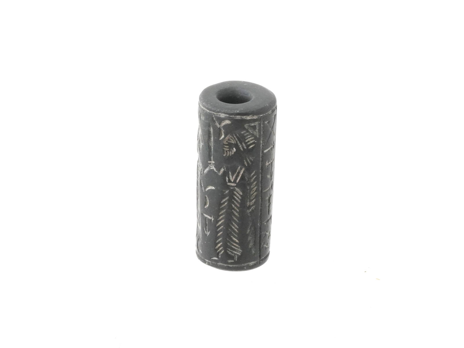 ANCIENT NEAR EASTERN CARVED HARDSTONE CYLINDER SEAL: An ancient Near Eastern cylinder shaped hand carved hard stone seal. The imprint depicts a scene with human figures and surrounded by ornaments. This seal, meticulously carved with intricate designs a