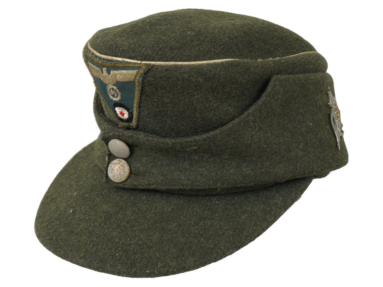 WWII NAZI GERMAN ARMY MOUNTAIN M43 FIELD CAP: A World War II German field cap, model M43 or Mountain Cap. Green wool visored cap with turn-down ear flaps secured in front by two buttons. Patch with SS Reichsadler decorates the front of the piece.