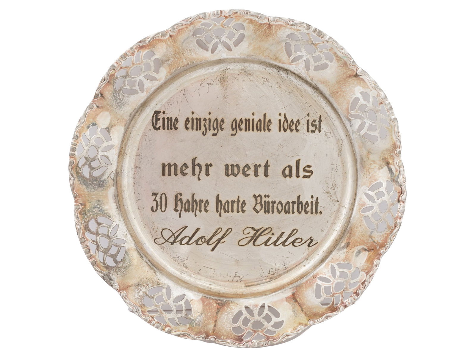 NAZI GERMAN WALL PLATE WITH ADOLF HITLER QUOTE: A Nazi German aluminum wall plate with pierced floral border. The center features an etched quote by Adolf Hitler in German: Eine einzige geniale Idee hat mehr Wert als 30 Jahre harte Buroarbeit, A si