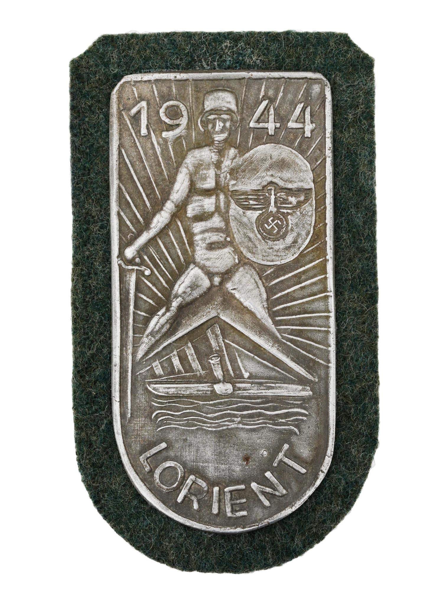 WWII TYPE GERMAN LORIENT CAMPAIGN 1944 SHIELD: A WWII type German military decoration The Lorient campaign 1944 Shield. The shield features a giant warrior above the submarine with a sword in one hand and a shield in the other. The date 1944 is lo