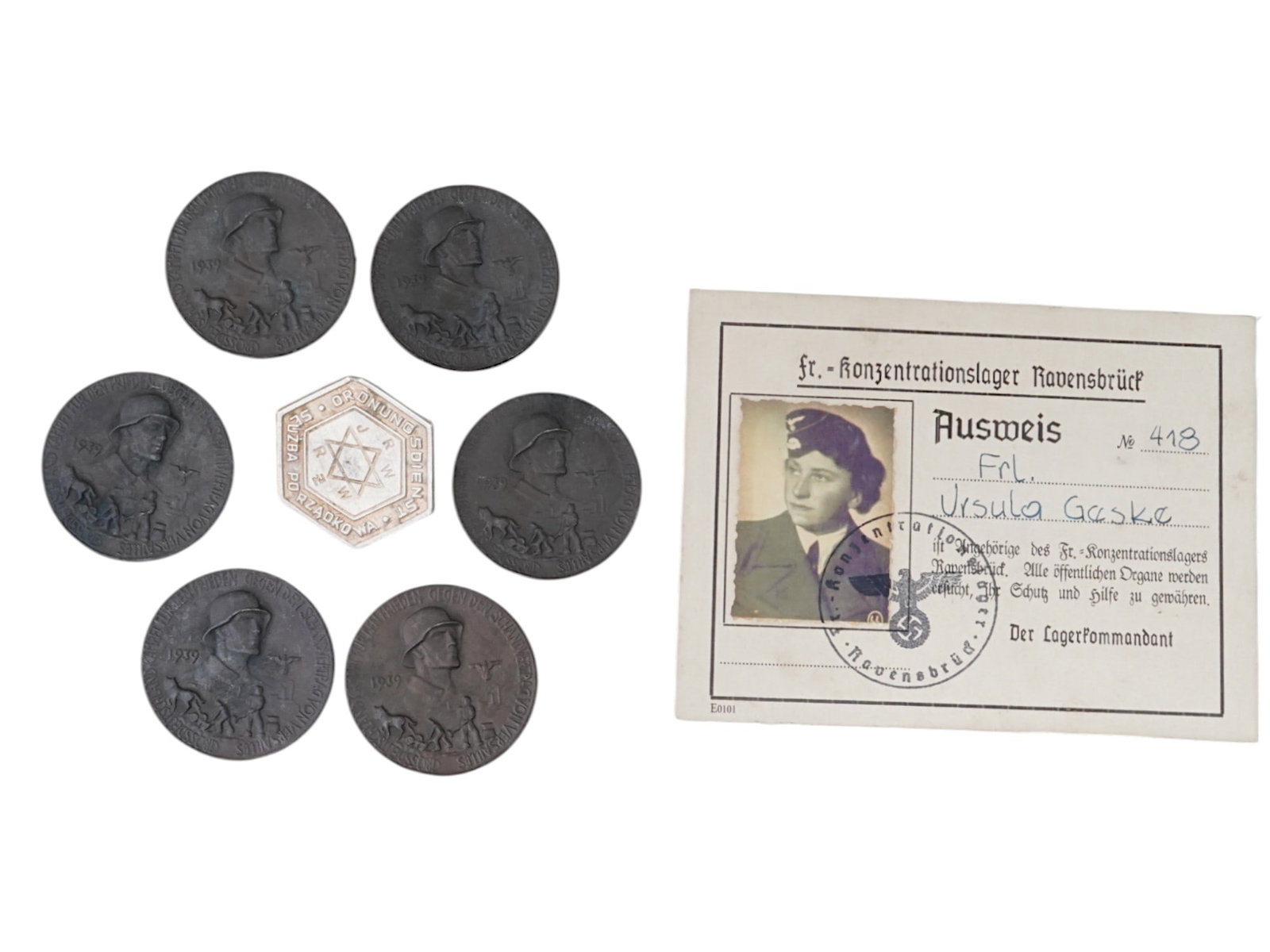 WWII ANTI SEMITIC RELICS AND RAVENSBRUCK CAMP GUARDS ID: A lot of 8 Holocaust period items. A German Ausweis or ID card of the SS concentration camp Ravensbruck guard, Ursula Geske, stamped, signed, with photograph. A badge of the Warsaw Ghetto police. A gr