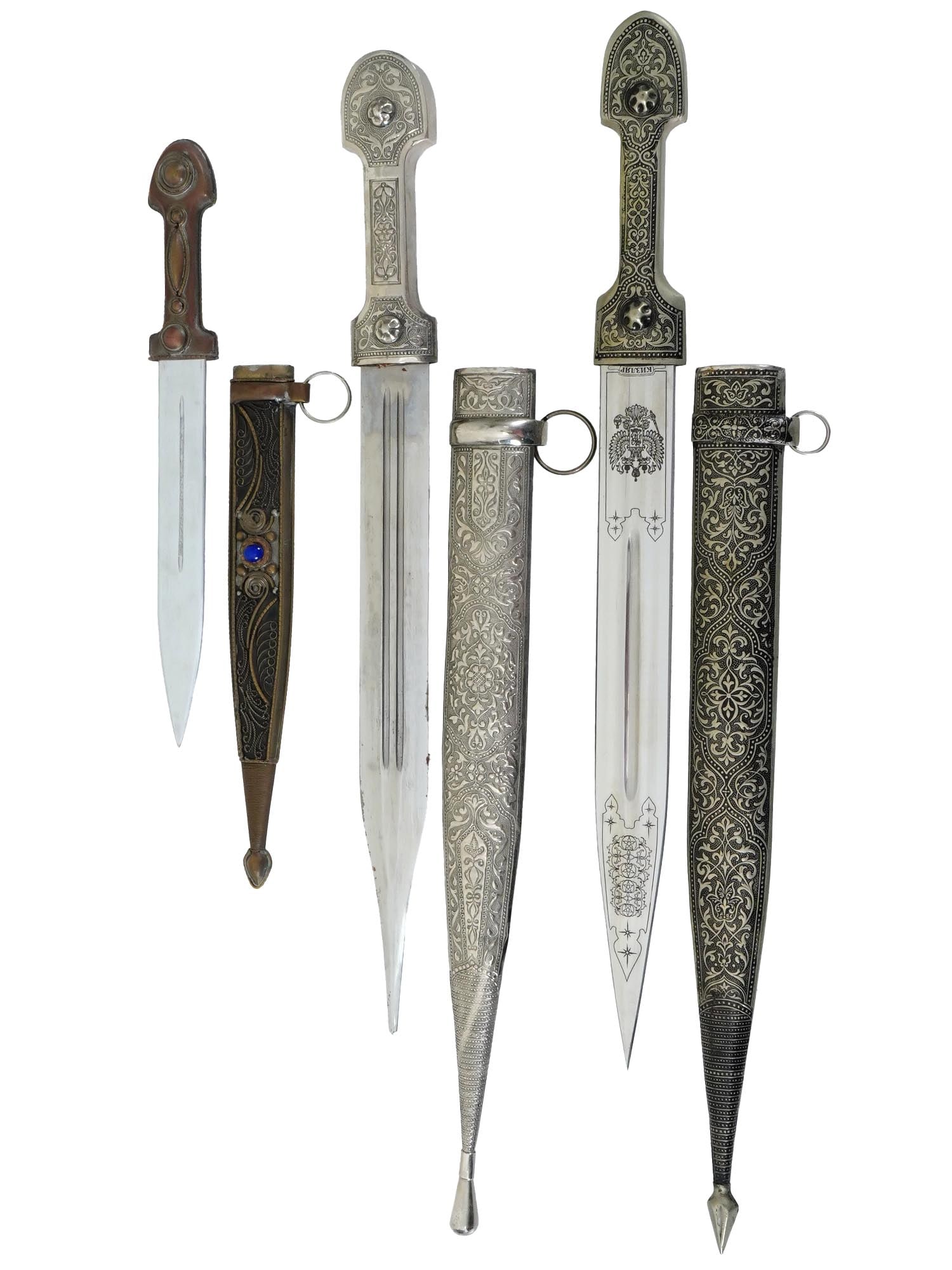 LOT OF THREE RUSSIAN CAUCASIAN KINJAL DAGGERS W DECOR: A lot of three Caucasian kinjal daggers with scabbards. Each features a distinct design with filigree and engraved foliage pattern. One is decorated with niello and bears an engraved Russian inscripti