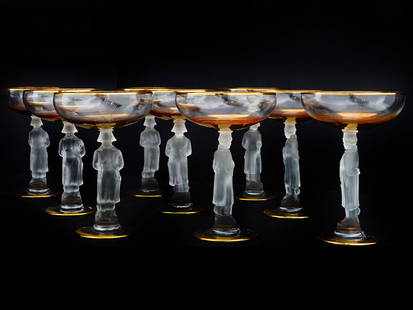 NAPOLEON BONAPARTE CRYSTAL CHAMPAGNE GLASSES: A set of 10 coupe glasses. Clear crystal pieces with gilt rims. The stems represent a full-length figure of Napoleon Bonaparte in frosted glass. The bowls bear an engraved N monogram with a crown. Unm