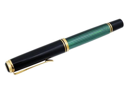 GERMAN PELIKAN SOUVERAN 18K GOLD FOUNTAIN PEN: A German Pelikan Souveran 18k gold fountain pen. The black and green body features an elegant, laconic design. The tip of the fountain pen is finely engraved and marked 18k for the 750 gold standard.