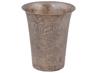 ANTIQUE PERSIAN QAJAR ENGRAVED SILVER SHOT CUP: An antique Persian silver shot cup. Qajar Empire, ca. 1900 to 1925. Taper shape, engraved floral ornaments and Arabic calligraphy. Leaf mark on the bottom. Total Weight: 158.23 grams. Oriental Islamic