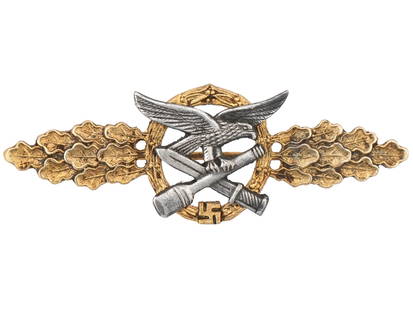 WWII NAZI GERMAN CLOSE COMBAT CLASP: A WWII Nazi German gilt military decoration, a Close Combat Clasp. The piece features a centerpiece consisting of the eagle and a crossed bayonet and hand grenade with, on each side, a spray of oak le