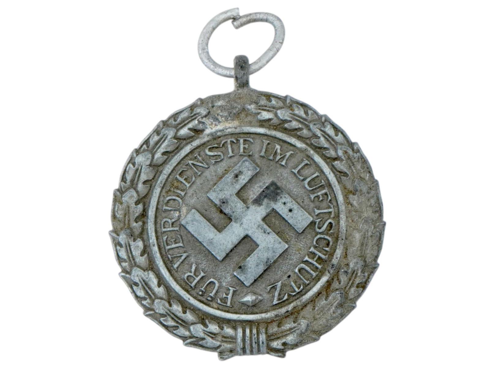 WWII NAZI GERMAN THIRD REICH AIR DEFENSE MEDAL 1938: A WWII Nazi German Third Reich Air Defense medal, second class, 1938. The medal features a relief image of a swastika in the center in an oak wreath and text in German around the circle: Fur Verdienst