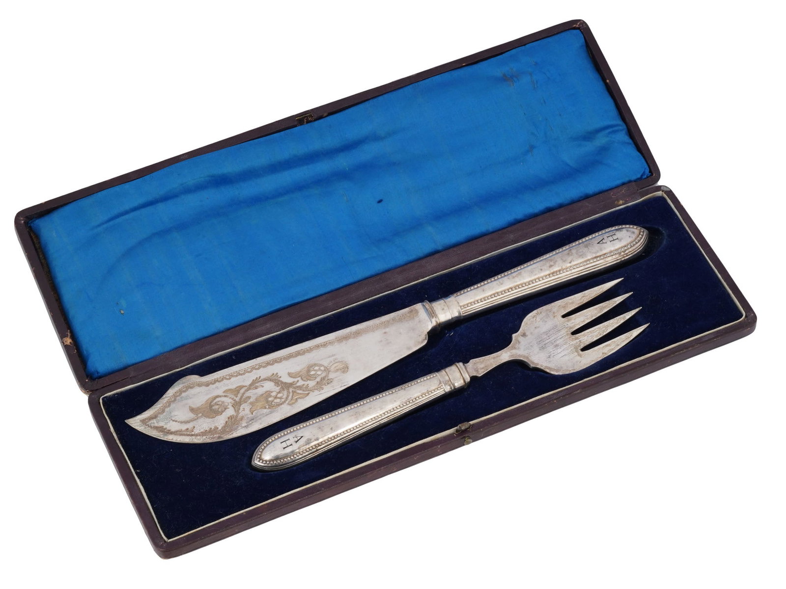WWII GERMAN ADOLF HITLER SILVER FISH FORK KNIFE SET: A WWII Nazi German silver tableware carving set consisting of a fork and a knife. The blade of the wide, slightly curved fish knife is decorated with engraved floral motifs on one side. The handles of