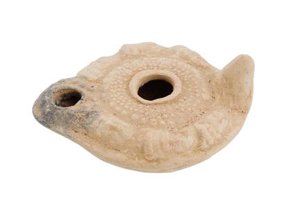 ANCIENT ROMAN TERRACOTTA CLAY OIL LAMP WITH FACES: An ancient Roman terracotta clay oil lamp. The rounded body of the lamp is adorned with a relief design representing faces on the edges and a raised handle. Its basic function was to provide light thr