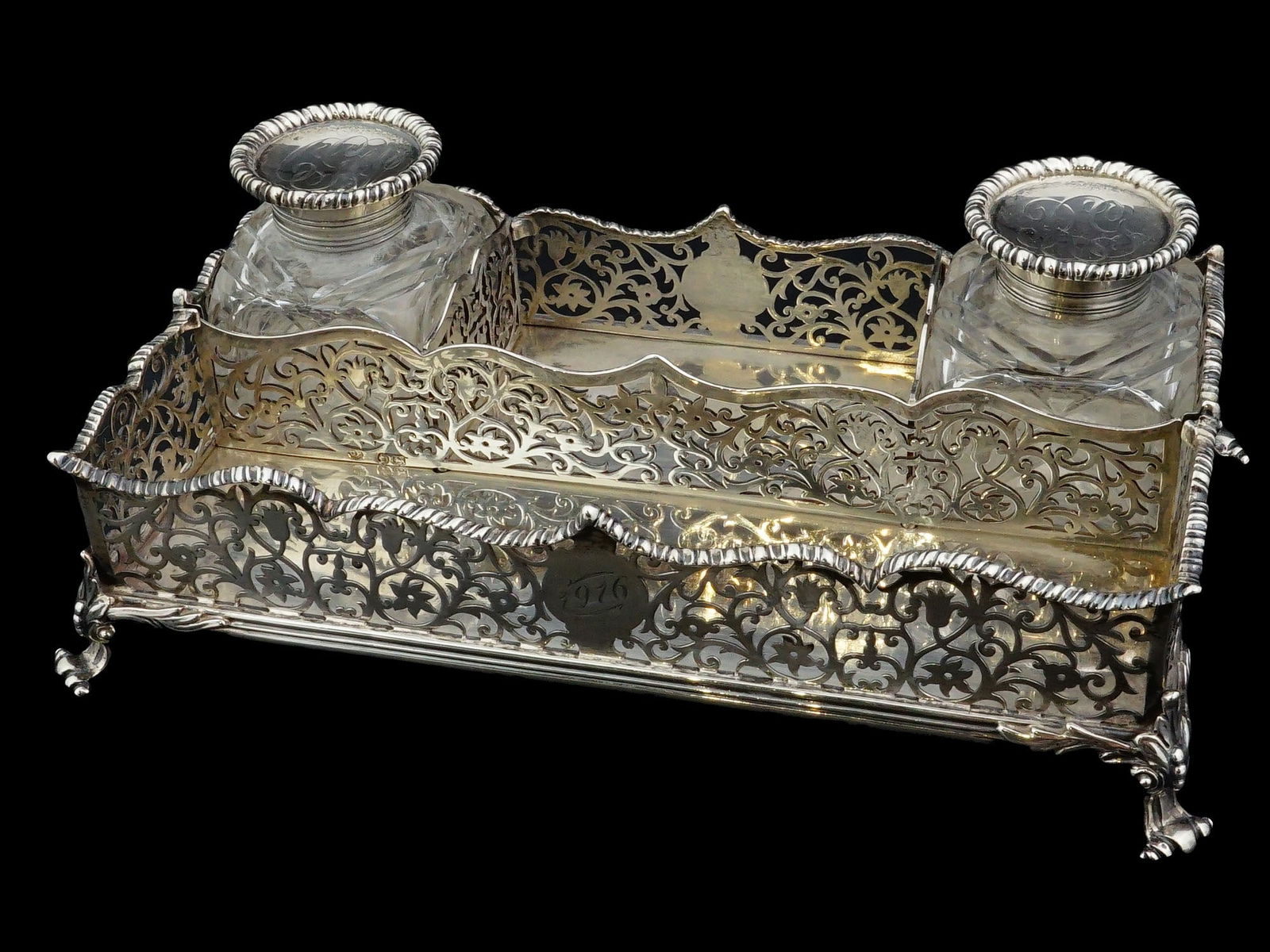 ANTIQUE CHARLES AND GEORGE FOXGLASS AND SILVER INKWELL: An antique British Charles and George Fox sterling silver inkwell in Victorian style, 1886. Has two glass and silver inkwells with hinged lids. The stand is adorned with an openwork scrolling floral d