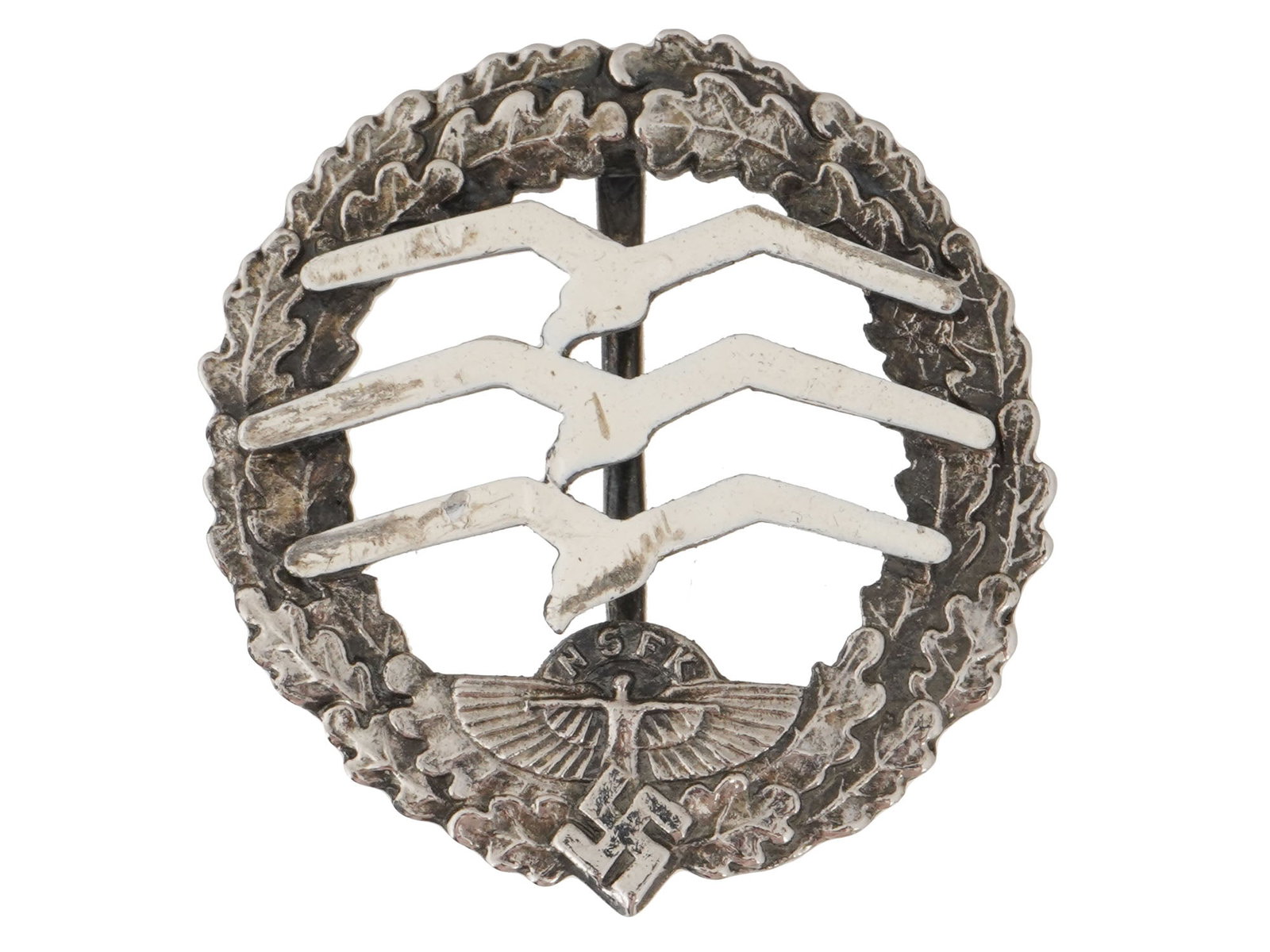 WWII TYPE GERMAN THIRD REICH NSFK GLIDER BADGE: A WWII type Nazi German Third Reich NSFK Glider Pilots badge. The darkened silvered oak leaf wreath with the winged man and swastika below the lettering NSFK, open centre with three individual affixed
