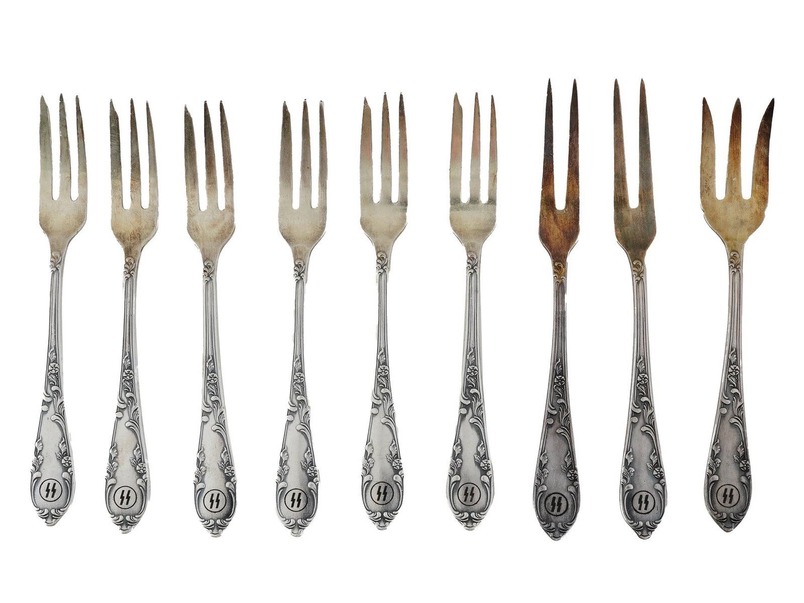WWII GERMAN FORKS FROM WAFFEN SS OFFICERS CANTEEN: A lot of WWII German forks from the Waffen SS officers canteen. A total of nine items. The forks have an etched SS emblem on the tip of the handle and are decorated with relief floral motifs. Hallmark