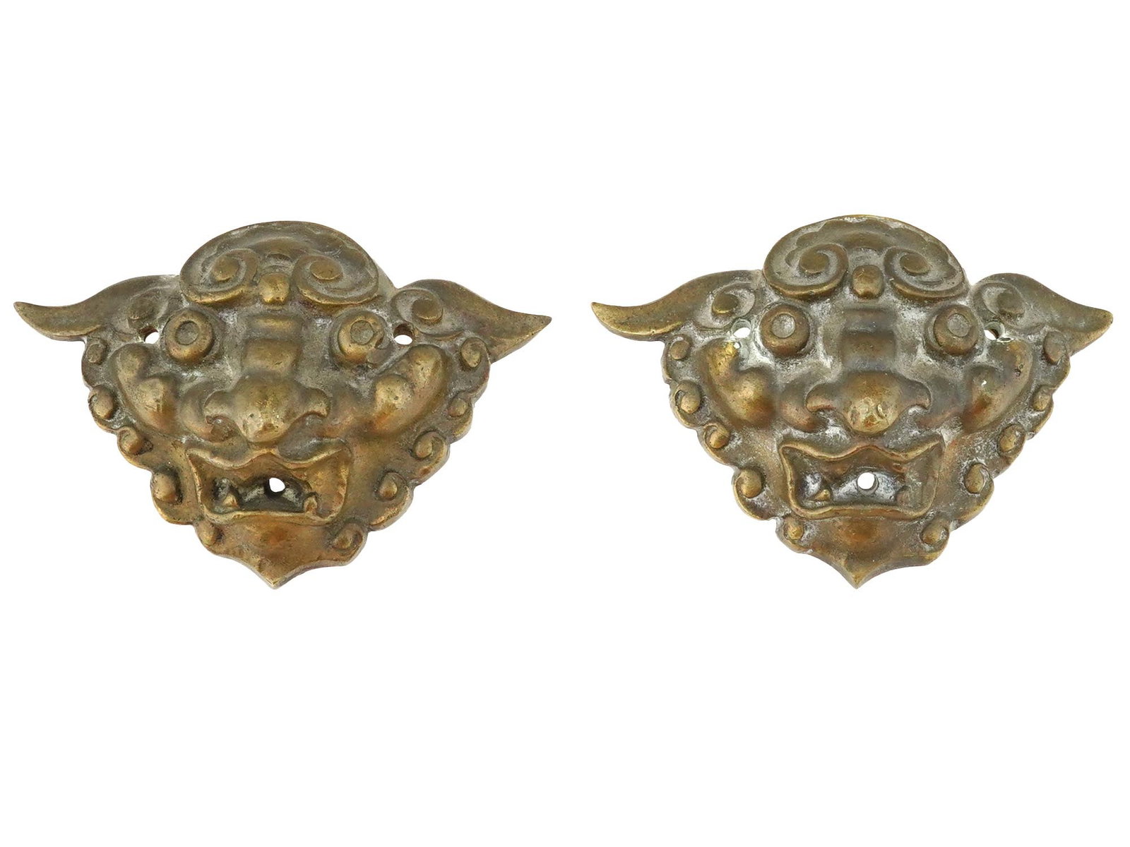 PAIR OF ASIAN BRONZE RELIEF MASKS OF MYTHICAL CREATURE: A pair of Asian bronze relief masks. The masks depict a stylized creature, possibly a lion or a mythical guardian figure, with fierce expressions, prominent teeth, and detailed facial features. Both m