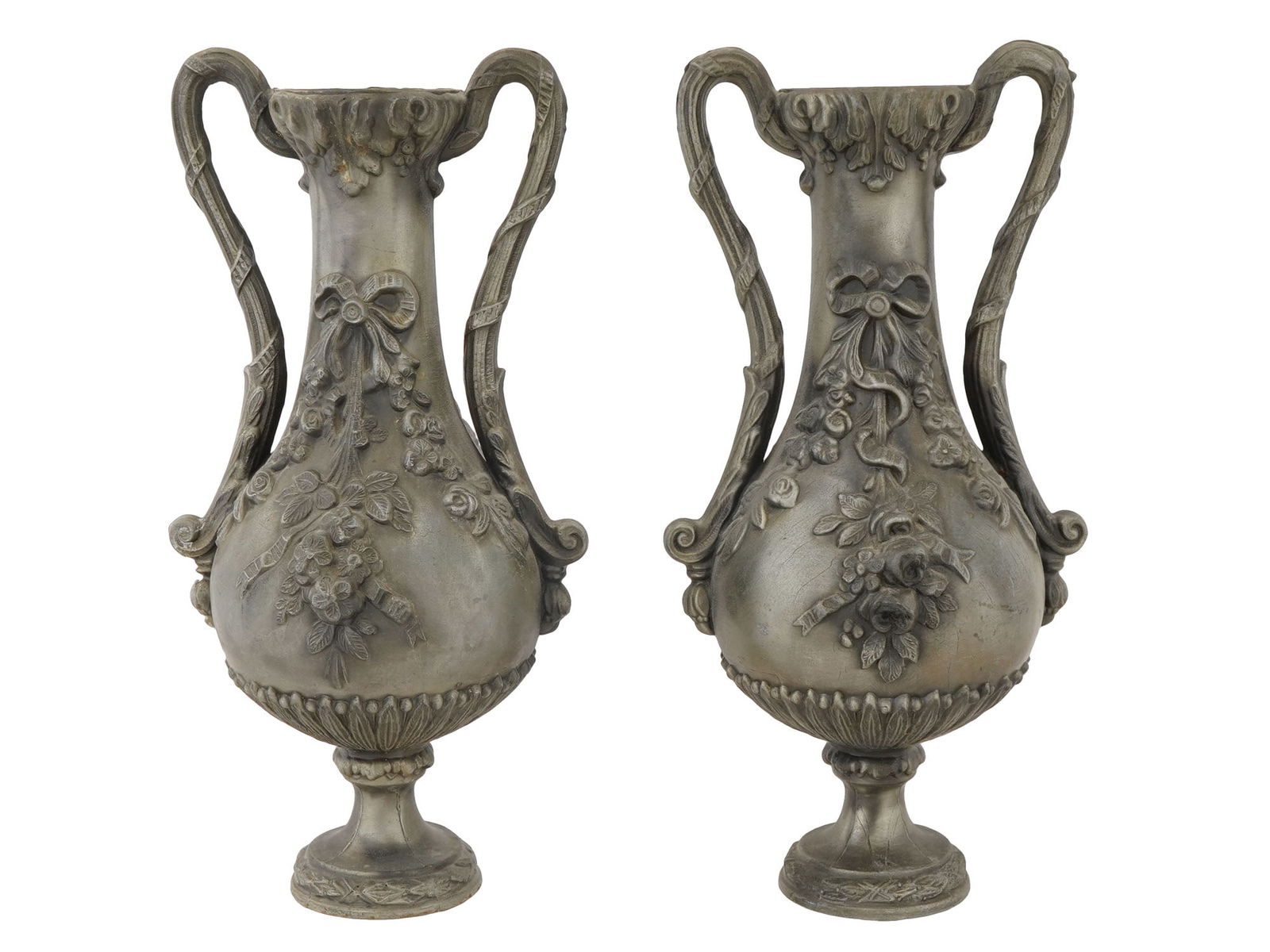 ANTIQUE FRENCH BRONZE URN VASES WITH FLORAL MOTIFS: A pair of antique French bronze urns, crafted in the late 19th century, each featuring gracefully curved foliage handles and adorned on both sides with ribbon knots and floral motifs in high relief. T
