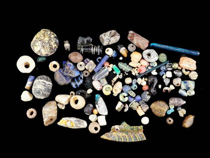 COLLECTION OF ANCIENT ROMAN GLASS BEADS FRAGMENTS: A collection of assorted ancient Roman glass fragments and beads. The collection includes beads in circular, and tubular shapes, various fragments in various abstract shapes. Ancient and Antique Roman