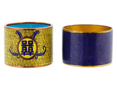 LOT OF TWO CHINESE BRASS CLOISONNE ENAMEL NAPKIN RINGS: A lot of two Chinese brass enamel napkin rings. Circa: early 20th century. One is adored with a yellow enamel ground with swirl pattern and a Chinese character with a blue enamel interior. The second