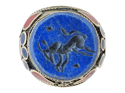 ANCIENT PERSIAN CARVED LAPIS LAZULI STONE SEAL RING: An ancient Persian hand carved Lapis Lazuli stone intaglio ring. The ring features a metal base set with a round cut Lapis Lazuli stone with an engraved image of a mythical creature or an animal. The