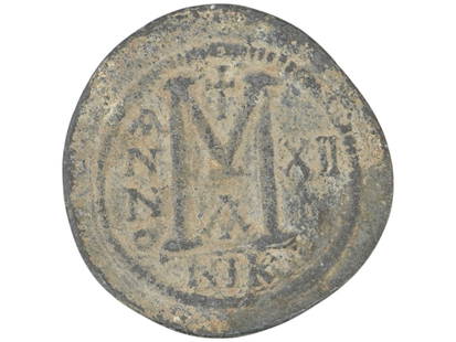 ANCIENT BYZANTINE BRONZE COIN 800 TO 1000 AD: An ancient Byzantine bronze coin, dating from circa 800 to 1000 AD. The obverse presents a helmeted and cuirassed bust of Emperor Justinian facing forward, depicted holding a cross on a globe in his r