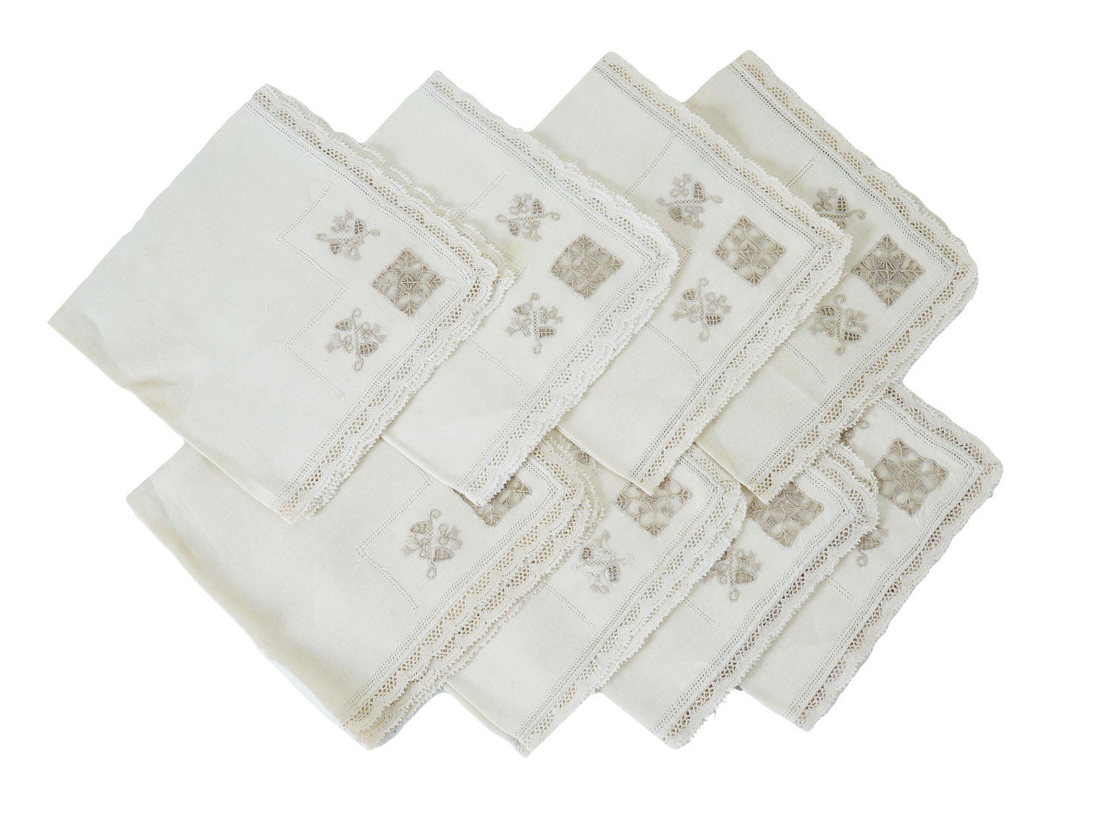 SET OF ANTIQUE NAPKINS WITH LACE TRIM: A set of antique napkins features delicate lace trim and intricately patterned embroidery at the corners. The light neutral tones and detailed craftsmanship emphasize the elegant and historical style