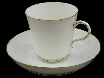 ANTIQUE FRENCH SEVRES PORCELAIN COFFEE CUP AND SAUSER: An antique French porcelain coffee cup and sauser by Sevres manufacture. Features a white teacup and saucer. The teacup has a simple, elegant design with a gild trim around the rim and handle. The sau