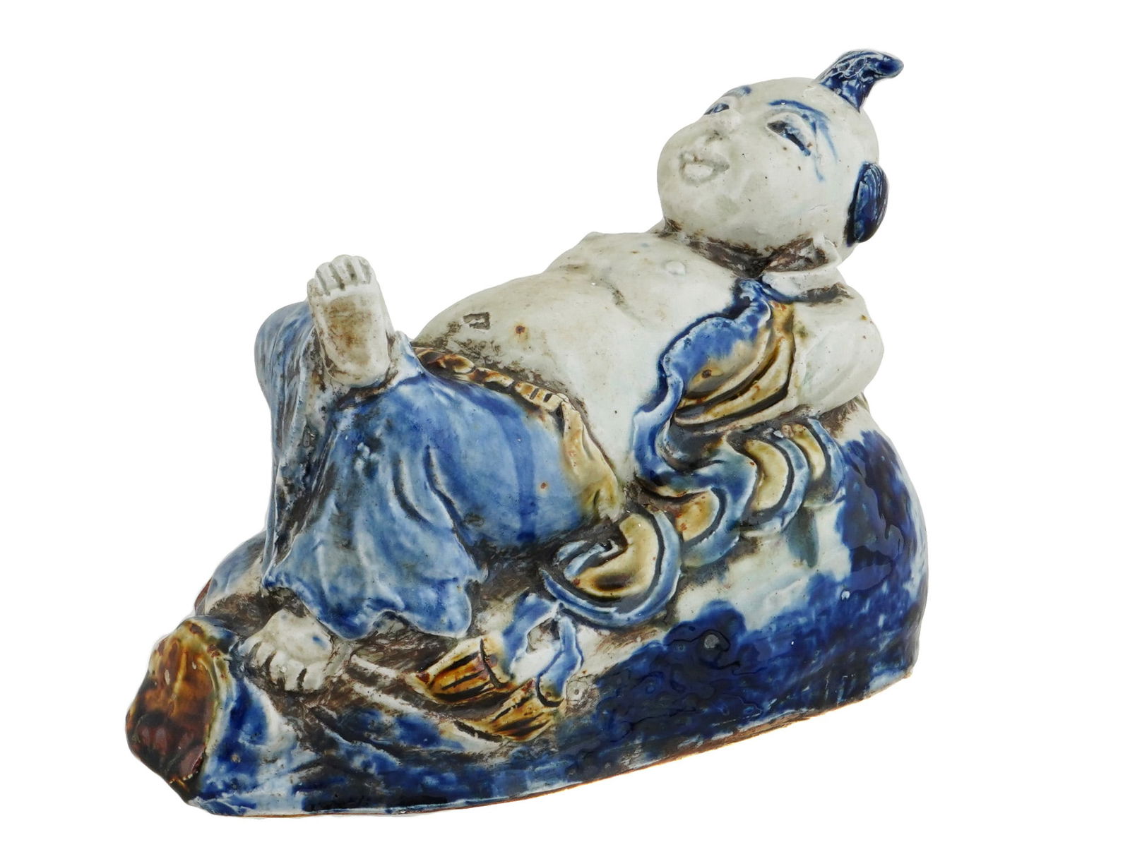 VIETNAMESE NGUYEN DYNASTY GLAZED CERAMIC BOY FIGURINE: An antique Vietnamese Nguyen Dynasty glazed ceramic figurine of a boy napping. Depicts the boy in a reclining position. He is resting on a platform that is painted in blue, brown, and white. The boy i