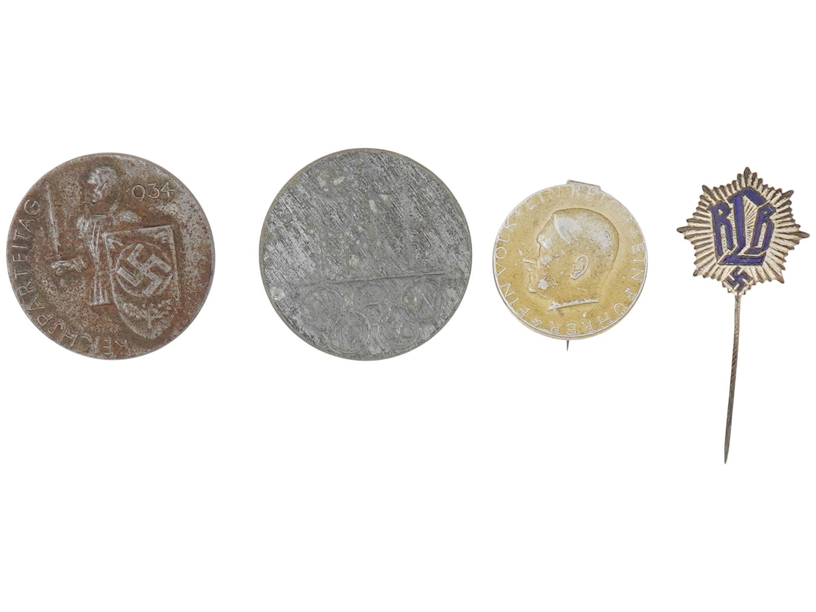 LOT OF FOUR WWII GERMAN NAZI THIRD REICH BADGES: A lot of four WWII German Nazi badges and pins. The lot includes the Adolf Hitler badge with a portrait of Adolf Hitler, inscribed around. The Reichsparteitag 1934 badge, Badge of a member of the Reic