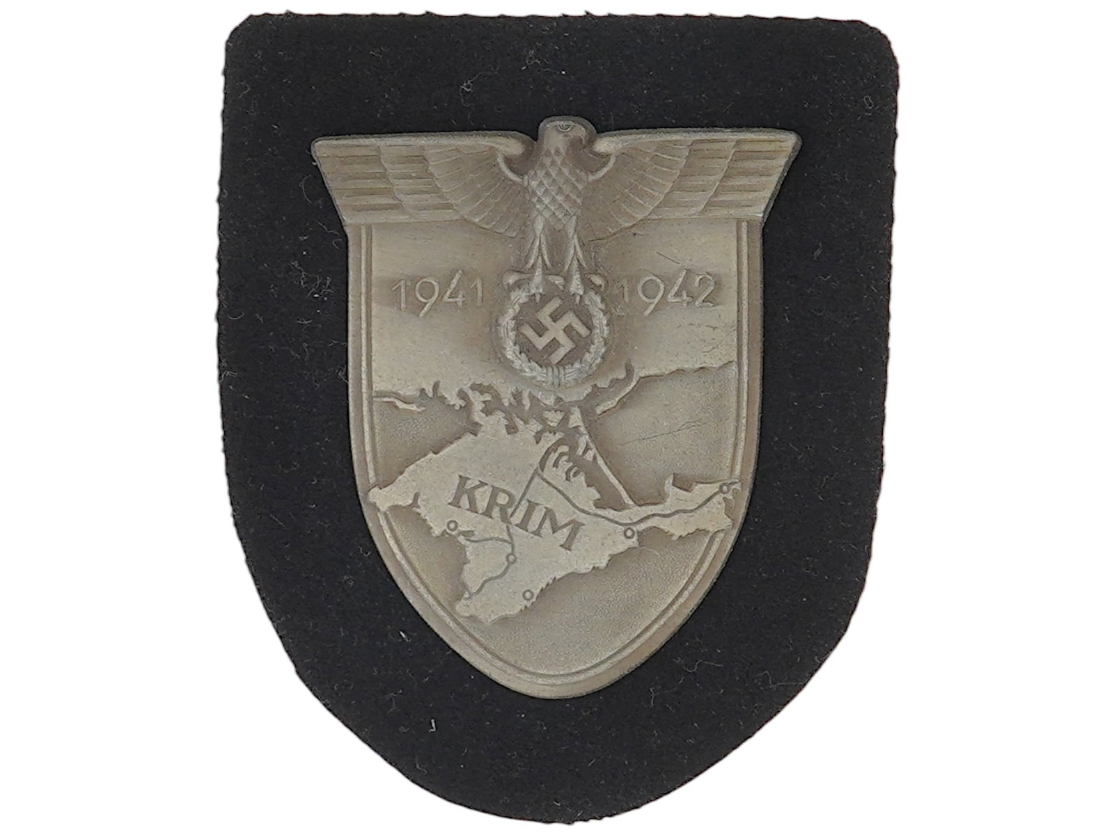 WWII GERMAN MILITARY KRIM DECORATION: A WWII German military Krim decoration. The Krim or Crimea shield is headed by the German eagle clutching a laurel wreath surrounding a swastika, flanked by the dates 1941 and 1942. This sits on a bac