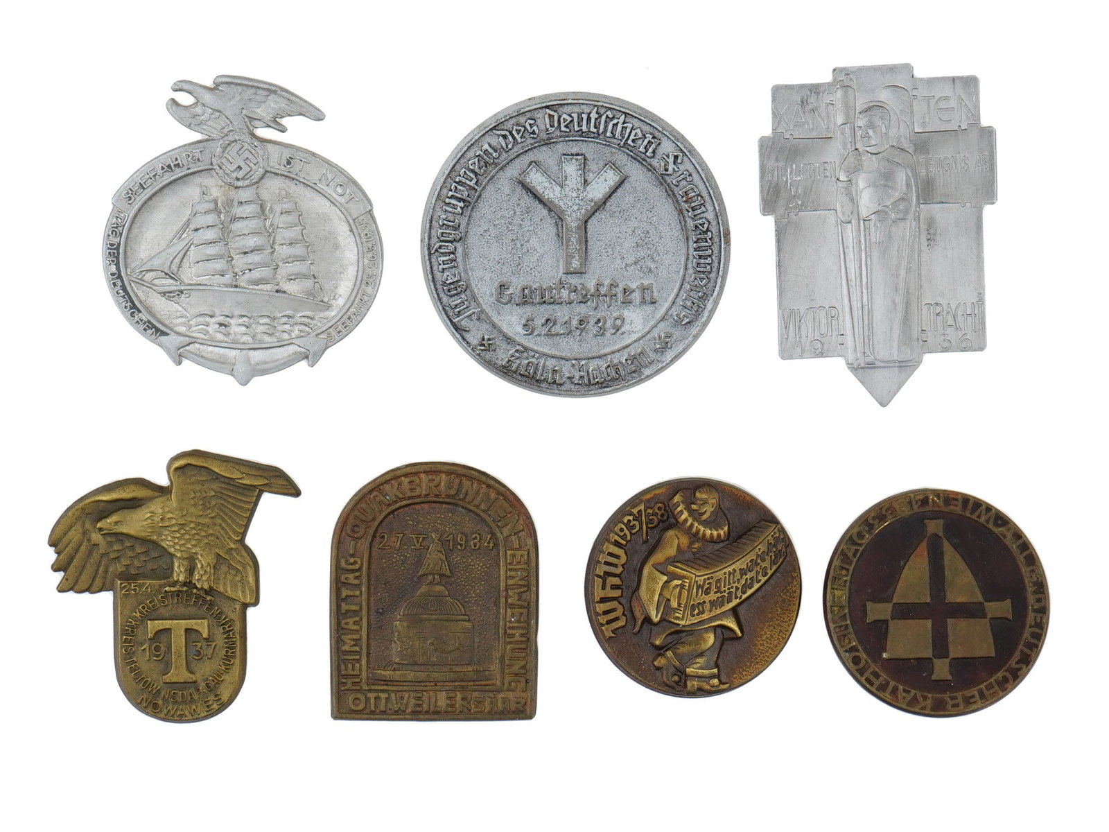 PRE WWII NAZI GERMAN THIRD REICH PROPAGANDA PIN BADGES: A group of seven pre-WWII German Third Reich pin badges, each representing key events or propaganda initiatives of the era. Included are a Sea Day 1935 badge, Victor von Xanten Martyrdom Celebration 1