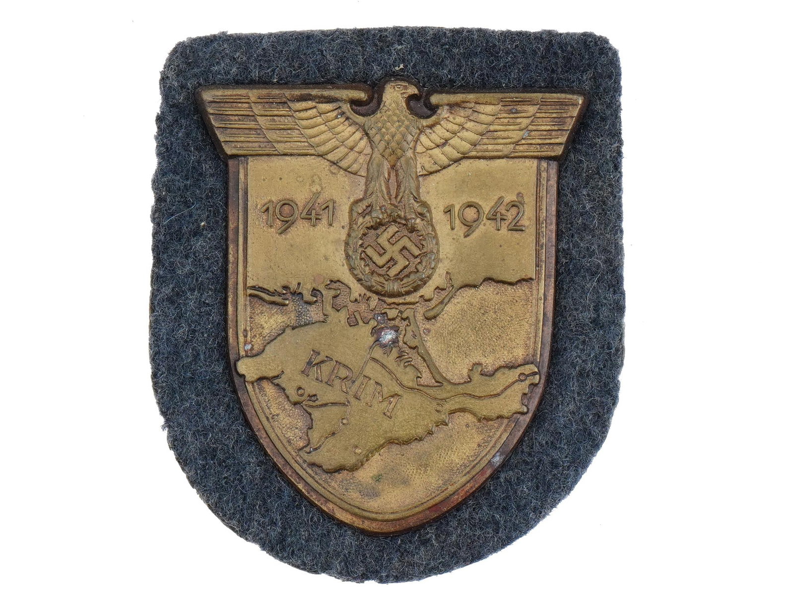 WWII GERMAN MILITARY KRIM DECORATION: A WWII German military Krim decoration. The Krim or Crimea shield is headed by the German eagle clutching a laurel wreath surrounding a swastika, flanked by the dates 1941 and 1942. This sits on a bac