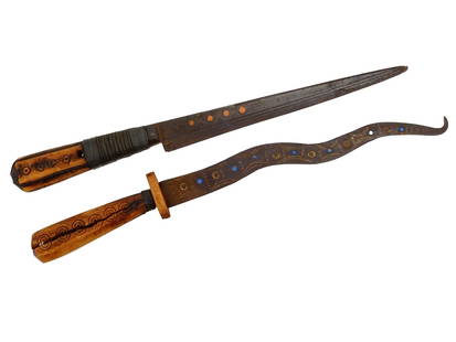 PAIR OF ANTIQUE AFRICAN CEREMONIAL KNIVES: A pair of antique African ceremonial knives. Circa the early 20th century. One of the knives has an elongated, straight shape. The metal blade is decorated on one side with engraved straight and wavy
