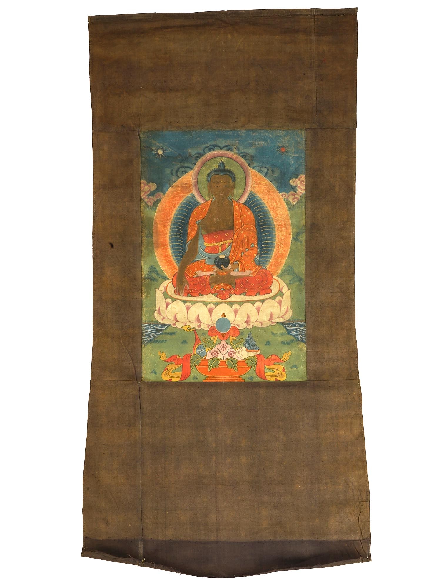 ANTIQUE CHINESE THANGKA PAINTING TIBET MEDICINE BUDDHA: An antique Chinese thangka painting from Tibet depicting the Medicine Buddha, Bhaishajyaguru, rendered in opaque pigments on cloth, with his right hand in the earth-touching position. His left hand, i