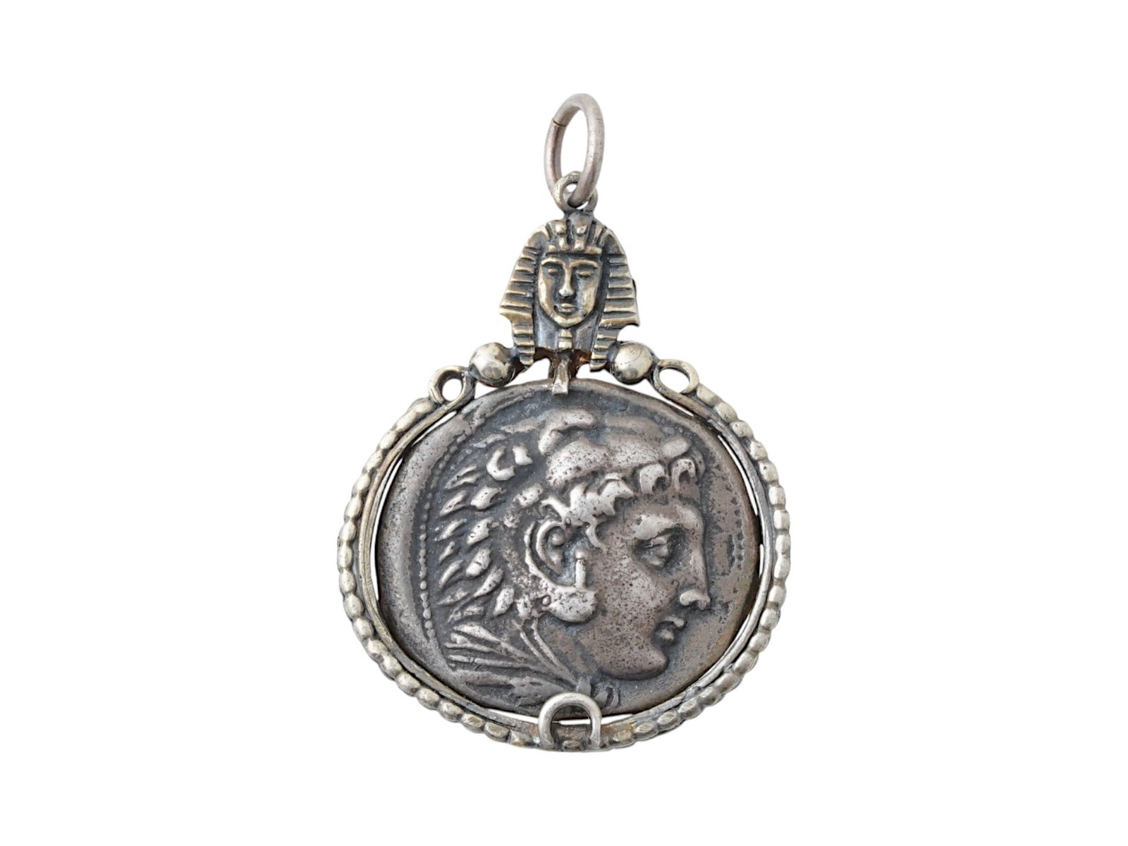 ALEXANDER THE GREAT TETRADRACHM SILVER COIN PENDANT: An ancient Greek silver Tetradrachm coin, Alexander the Great rule, ca. 336 to 323 BC. The coin is set in a silver setting pendant, crowned with a detailed pharaoh motif at the top.. Antique Jewelry A