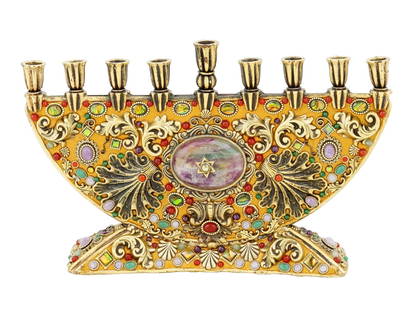 VINTAGE JUDAICA BRASS HANUKKAH MENORAH BY MICHAL GOLAN: A vintage Judaica brass Hanukkah menorah from the 20th century. The lamp has an ornate, decorative design. It is primarily gold in color and is heavily embellished with colorful enamel and stones of v
